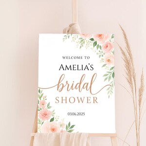 Op de afbeelding: Een wit bord met een bloemenontwerp in roze en groene tinten. De tekst op het bord luidt "Welkom bij Amelia's Bridal Shower 03.06.2025".