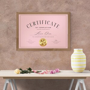 Puede incluir: Un certificado de finalizaci&oacute;n rosa con un sello dorado, enmarcado en madera marr&oacute;n. El certificado se entrega a Laura Dorn por completar el curso de t&eacute;cnica de pesta&ntilde;as.