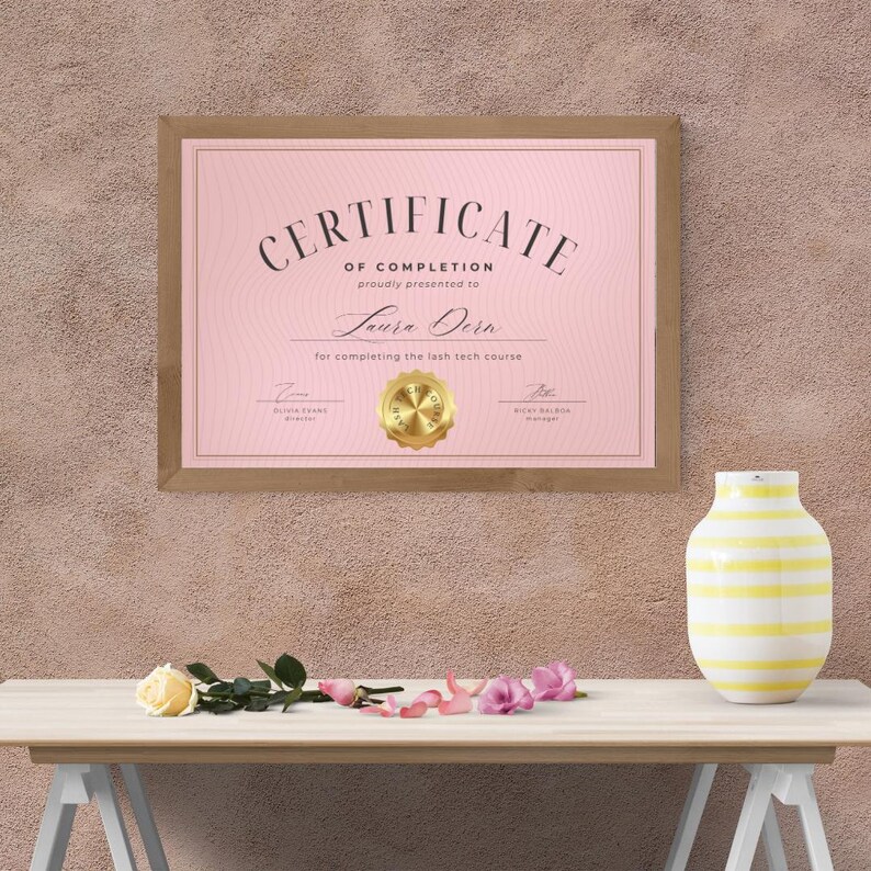 Puede incluir: Un certificado de finalizaci&oacute;n rosa con un sello dorado, enmarcado en madera marr&oacute;n. El certificado se entrega a Laura Dorn por completar el curso de t&eacute;cnica de pesta&ntilde;as.