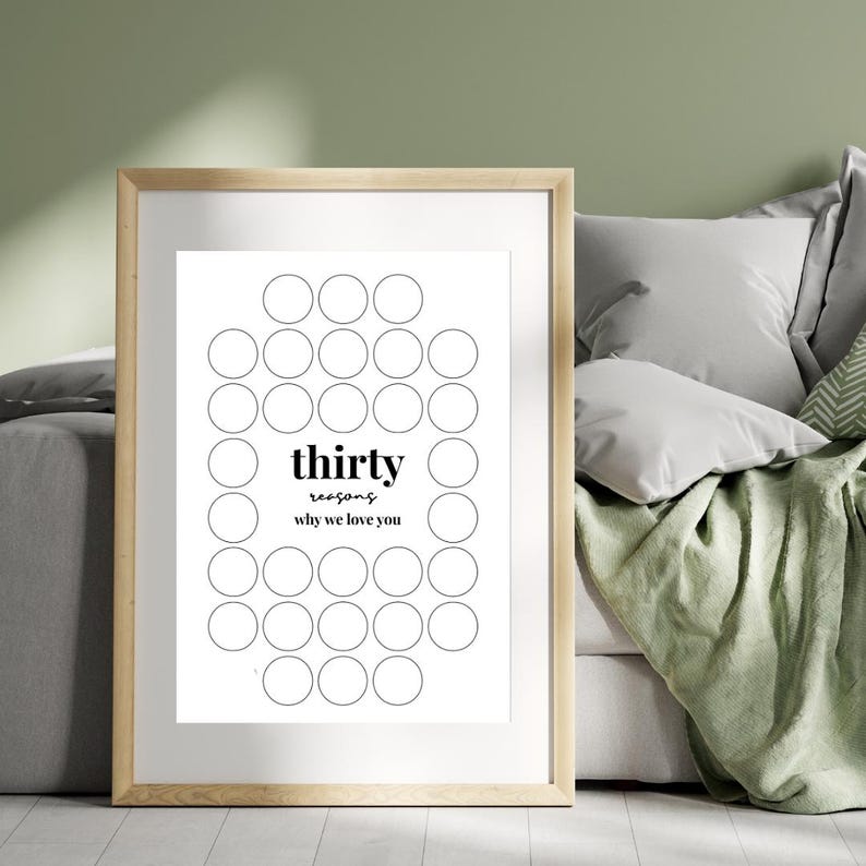 以下が含まれることがあります： 白い背景に「thirty reasons why we love you」と書かれた黒い文字が入った額入りのプリント。プリントには、楕円形に配置された一連の円が描かれています。フレームは明るい木の色です。
