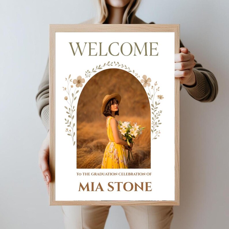 May include: A welcome sign with a floral archway and a photo of a person in a yellow dress and a straw hat. The text on the sign reads "Welcome to the graduation celebration of Mia Stone".
