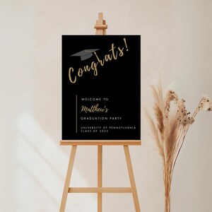 K&ouml;nnte beinhalten: Schwarzes Abitur-Partyschild mit goldenen Buchstaben, auf dem "Herzlichen Gl&uuml;ckwunsch!" und "Willkommen zur Abschlussparty von Matthew University of Pennsylvania Klasse 2023" steht.
