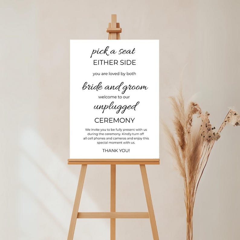 May include: White sign with black text that reads "pick a seat either side you are loved by both bride and groom welcome to our unplugged ceremony we invite you to be fully present with us during the ceremony kindly turn off all cell phones and cameras and enjoy this special moment with us thank you!"