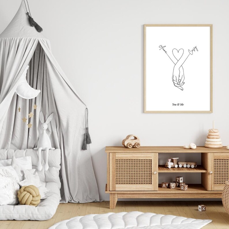 May include: A black and white line art print of two hands holding each other with a heart in the middle. The names "Amy" and "Casey" are written above the hands. The text "You & Me" is below the hands.
