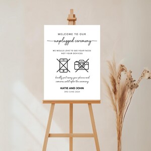 Puede incluir: Un cartel blanco con texto negro e iconos que anuncian una ceremonia de boda sin dispositivos electr&oacute;nicos. El cartel dice "Bienvenido a nuestra ceremonia sin dispositivos electr&oacute;nicos. Nos encantar&iacute;a ver sus caras, no sus dispositivos". Tambi&eacute;n incluye iconos de un tel&eacute;fono y una c&aacute;mara con una l&iacute;nea diagonal que los atraviesa. El cartel tambi&eacute;n incluye los nombres "Katie y John" y la fecha "3rd June 202X".