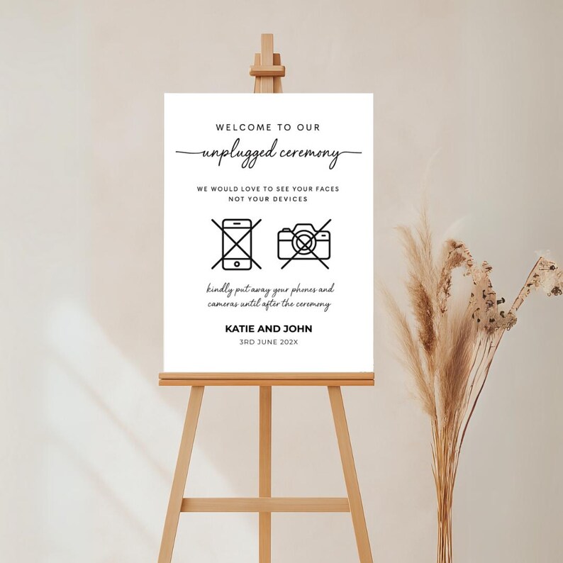 Puede incluir: Un cartel blanco con texto negro e iconos que anuncian una ceremonia de boda sin dispositivos electr&oacute;nicos. El cartel dice "Bienvenido a nuestra ceremonia sin dispositivos electr&oacute;nicos. Nos encantar&iacute;a ver sus caras, no sus dispositivos". Tambi&eacute;n incluye iconos de un tel&eacute;fono y una c&aacute;mara con una l&iacute;nea diagonal que los atraviesa. El cartel tambi&eacute;n incluye los nombres "Katie y John" y la fecha "3rd June 202X".
