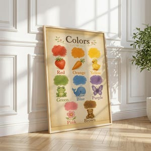 May include: A framed educational wall art print titled Colors, featuring watercolour-style illustrations of a red strawberry, orange carrot, yellow duck, green frog, blue whale, purple butterfly, pink flower, and brown teddy bear on a beige background.