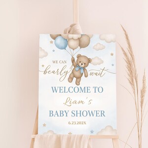May include: A blue and brown baby shower welcome sign with a teddy bear holding balloons. The sign says "We can bearly wait" and "Welcome to Liam's Baby Shower 6.23.202X".