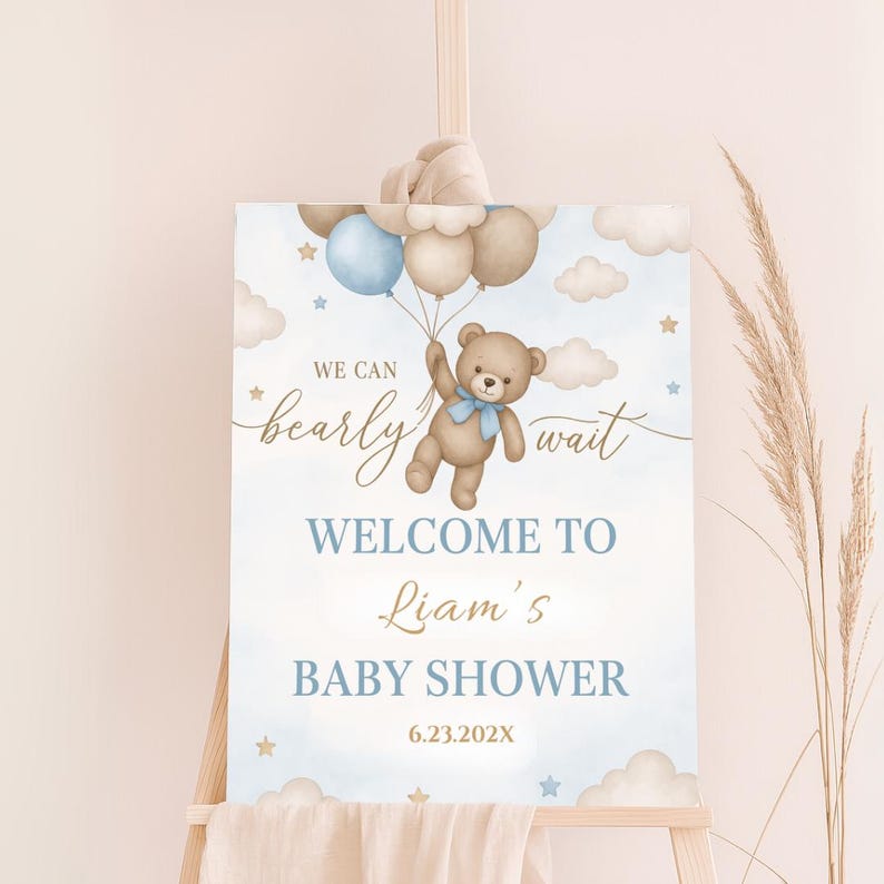May include: A blue and brown baby shower welcome sign with a teddy bear holding balloons. The sign says "We can bearly wait" and "Welcome to Liam's Baby Shower 6.23.202X".