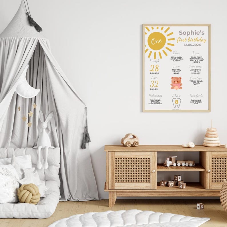 May include: A yellow and white printable first birthday poster with a sun graphic and the text "One" and "Sophie's first birthday 12.05.20XX". The poster lists the child's weight, height, favorite foods, and things they can do.