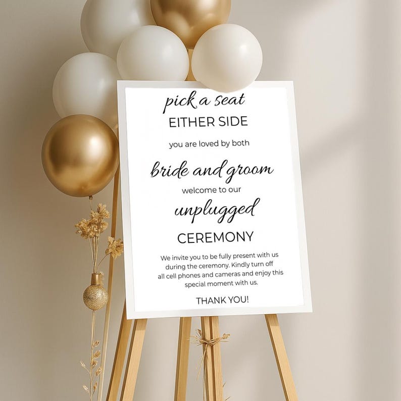 May include: White sign with black text on an easel. The sign reads "pick a seat either side you are loved by both bride and groom welcome to our unplugged ceremony we invite you to be fully present with us during the ceremony. Kindly turn off all cell phones and cameras and enjoy this special moment with us. thank you!"