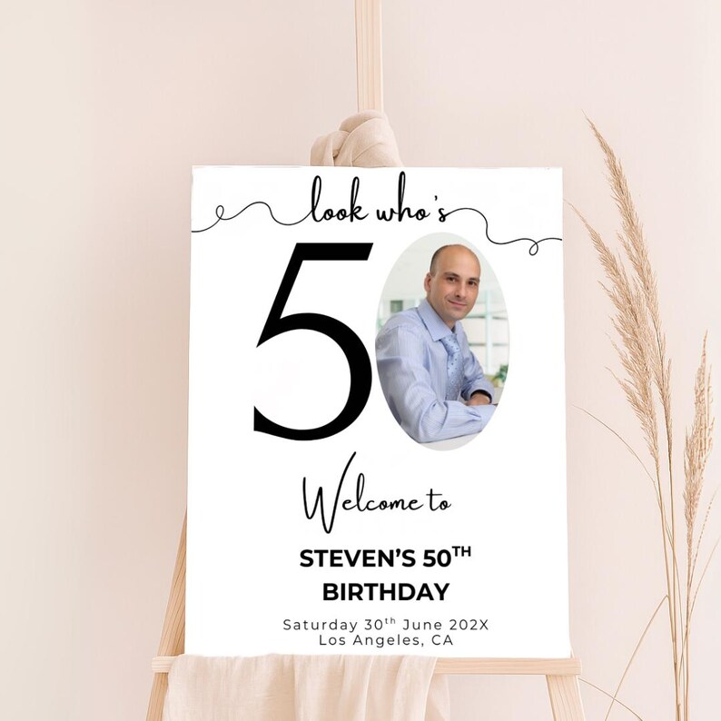 May include: A white sign with black text and a photo of a man. The sign says "Look who's 50. Welcome to Steven's 50th Birthday. Saturday 30th June 202X. Los Angeles, CA."