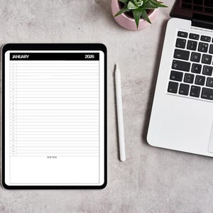 Op de afbeelding: Een digitale planner op een zwarte tablet, met een kalenderindeling voor januari 2026 met gelijnde secties voor notities. Een witte stylus ligt naast de tablet. Een laptop en een kleine potplant zijn ook zichtbaar op een grijze ondergrond.