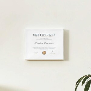 以下が含まれることがあります： 上部に「CERTIFICATE OF PARTICIPATION」というテキストが書かれた白い参加証明書。証明書の真ん中には「Stephen Lawrence」という名前が印刷されています。証明書には金色の印鑑と署名があります。