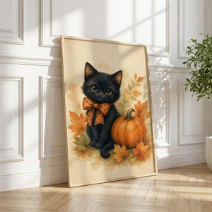 May include: A framed wall art print featuring a watercolor illustration of a fluffy black kitten wearing an orange polka-dot bow tie, sitting next to a large orange pumpkin surrounded by scattered autumn leaves in shades of yellow and orange.