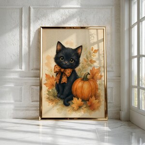 May include: A framed wall art print featuring a fluffy black kitten with large eyes wearing an orange polka-dot bow tie. The kitten sits next to a round orange pumpkin surrounded by scattered autumn leaves in shades of yellow and orange.