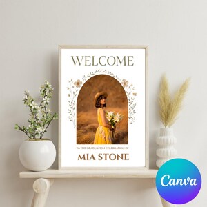 May include: Welcome sign with a floral arch and a photo of a person in a yellow dress holding flowers. The text on the sign reads "Welcome to the graduation celebration of Mia Stone".