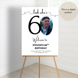 May include: A black and white welcome sign for a 60th birthday party. The sign says "Look who's 60" with a photo of the birthday person in a circle. The sign also says "Welcome to Steven's 60th Birthday" and includes the date and location of the party.
