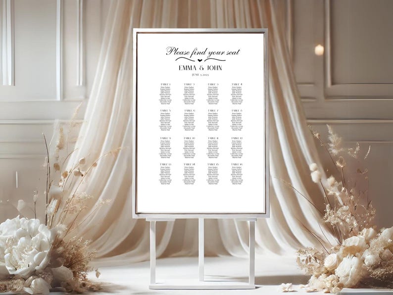 K&ouml;nnte beinhalten: Wei&szlig;e Hochzeitssitzordnung mit silbernem Rahmen auf einem wei&szlig;en Staffelei. Die Karte hat den Text "Bitte finden Sie Ihren Platz" und "Emma & John" mit einem kleinen Herzsymbol. Die Karte listet Tischnummern und G&auml;stelisten auf.