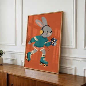 Peut inclure: Une impression d'art encadr&eacute;e repr&eacute;sentant un lapin gris portant un casque jaune et un pull bleu sarcelle, patinant sur des patins &agrave; roulettes bleus tout en tenant un lecteur de cassette bleu sur un fond orange uni.