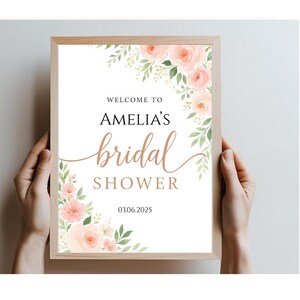 Op de afbeelding: Een wit bord met een bloemige rand en de tekst "Welkom bij Amelia's bruidsdouche 03.06.2025"