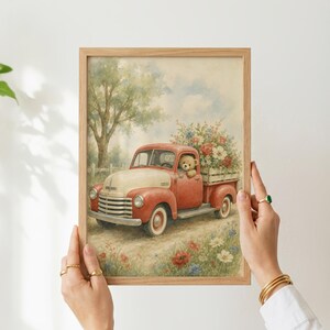 May include: A framed watercolor print featuring a vintage red and cream pickup truck driven by a teddy bear. The truck bed is filled with a large bouquet of colorful flowers. The scene is set on a dirt path with wildflowers and trees.