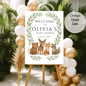 May include: Welcome to Olivia's Baby Shower sign with a green leafy wreath and four woodland animals: a bear, moose, fox, and raccoon. The date is June 3rd, 202X.