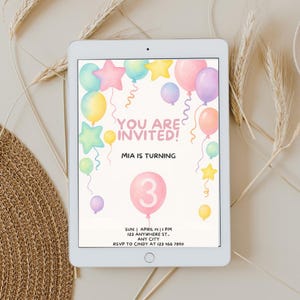 Op de afbeelding: Een digitale tablet met een verjaardagsuitnodiging versierd met pastelkleurige ballonnen en sterren. De tekst luidt: YOU ARE INVITED! MIA IS TURNING 3. SUN. APRIL 14 | 1 PM 123 ANYWHERE ST. ANY CITY RSVP TO CINDY AT 123 456 7890. Zachte kleurtinten.