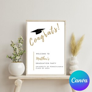 K&ouml;nnte beinhalten: Ein wei&szlig;es Schild mit einer goldenen Abschluss-Kappe und dem Text "Congrats!" in goldener Schrift. Das Schild zeigt auch "Willkommen zur Abschlussfeier von Matthew, University of Pennsylvania, Klasse von 2025".