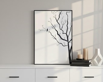 May include: A framed black and white art print featuring a minimalist tree silhouette with a perched bird. The artwork is displayed on a white cabinet, alongside candles, books, and a decorative vase. The overall aesthetic is modern and serene.