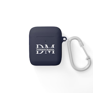 Puede incluir: Una funda para Airpods de color azul marino con un mosquetón plateado. La funda tiene las letras "DM" con el texto "Dungeon Master" debajo.