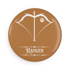Puede incluir: Un botón marrón con un contorno blanco de un arco y una flecha con una huella de pata en el centro. El texto "RANGER" está debajo del arco y la flecha.