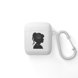 May include: White Airpods case with a black silhouette of a woman with a book inside her head. The case has a silver carabiner attached.