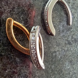 May include: Two pairs of hoop earrings with a row of clear cubic zirconia stones. One pair is gold and the other is silver.