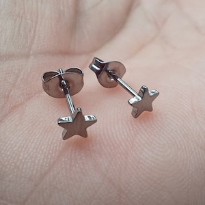 May include: A pair of silver star stud earrings. The earrings are small and have a simple design.
