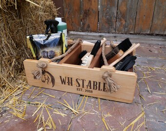 May include: Wooden grooming box with a horse head logo and the text "WH STABLE EST. 2018". The box has rope handles and contains various horse grooming brushes.