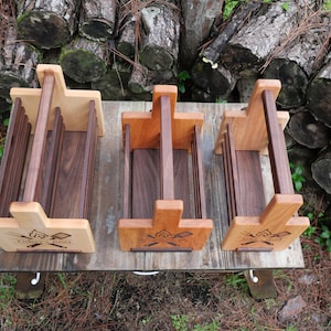 K&ouml;nnte beinhalten: Drei Holzkisten mit Griffen. Die Kisten sind aus verschiedenen Holzarten gefertigt, darunter Walnuss und Ahorn. Jede Kiste hat ein Design aus gekreuzten &Auml;xten und den Text "The Original Grill" auf der Vorderseite.