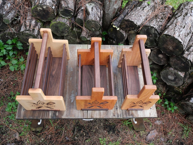 K&ouml;nnte beinhalten: Drei Holzkisten mit Griffen. Die Kisten sind aus verschiedenen Holzarten gefertigt, darunter Walnuss und Ahorn. Jede Kiste hat ein Design aus gekreuzten &Auml;xten und den Text "The Original Grill" auf der Vorderseite.