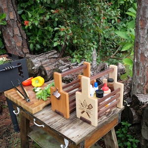 K&ouml;nnte beinhalten: Zwei Grill-Caddies aus Holz mit Griffen. Der Caddy rechts hat den Text "Dad's BBQ" auf der Vorderseite eingraviert. Beide Caddies haben Flaschenhalter und einen integrierten Flaschen&ouml;ffner.