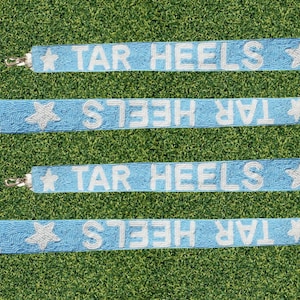 May include: Four light blue beaded straps with white beads spelling "TAR HEELS" and a white star at the end of each strap.