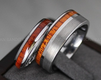May include: Two wedding bands, one with a silver band and a wooden inlay, the other with a silver band and a wooden inlay with a silver stripe.
