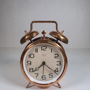 Op de afbeelding: Een witte keramische mok met een zwart handvat en de tekst "But First, Coffee" in een zwarte, vette letter. De mok staat op een wit oppervlak.