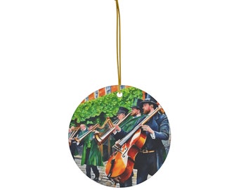 Könnte beinhalten: Ein runder Keramik-Anhänger mit einer Aquarellmalerei einer Gruppe von Musikern, die in einer Straßenszene Instrumente spielen. Die Musiker tragen grüne und schwarze Kleidung und spielen Harfe, Cello und andere Instrumente. Die Szene spielt vor dem Hintergrund eines Backsteingebäudes und grüner Blätter.