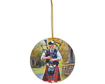 May include: A round ceramic ornament featuring a painting of a man in a kilt playing bagpipes. The man is standing on a path with trees and a stone wall in the background. The text "Scotland" is written in red on the ornament.