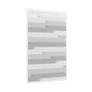 Op de afbeelding: Een grote, rechthoekige kalender voor 2026 in grijstinten en wit. De kalendergrid is verdeeld in maanden en dagen, met de titel van het jaar bovenaan. De maanden zijn gelabeld en het algehele ontwerp is minimalistisch en modern.