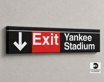 May include: A rectangular black sign featuring a white downward-pointing arrow, the word Exit in white text on a red background, and the white text Yankee Stadium. The sign includes a small white square logo in the corner reading MTA Officially Licensed.