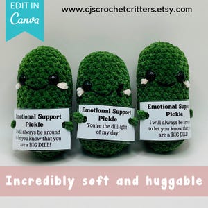 May include: Three green crocheted pickle plushies with black eyes and white accents. Each pickle holds a sign that reads "Emotional Support Pickle" with a unique message. The text "Incredibly soft and huggable" is at the bottom.