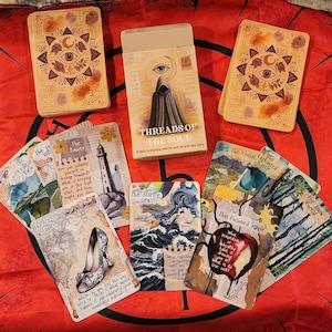 May include: A deck of Threads of the Soul oracle cards featuring a box with a hooded figure and an eye symbol. The cards display various illustrations including a lighthouse, a high-heeled shoe, a stormy sea, and a poisoned apple with text.