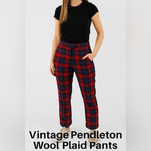 May include: Red, navy, and black plaid wool pants with a straight leg. The pants have a button and zipper closure and pockets. The text "VINTAGE PENDLETON WOOL PLAID PANTS" is at the bottom of the image.