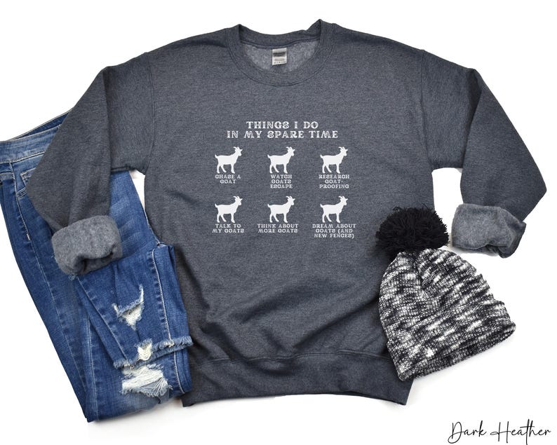 May include: Dark heather gray sweatshirt with the text "THINGS I DO IN MY SPARE TIME" and goat illustrations. The sweatshirt is paired with blue jeans and a black and white beanie.